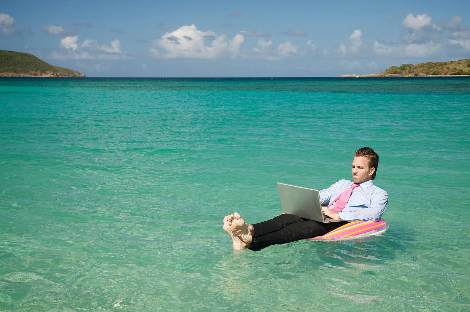 A businessman working while on vacation at a beach.
