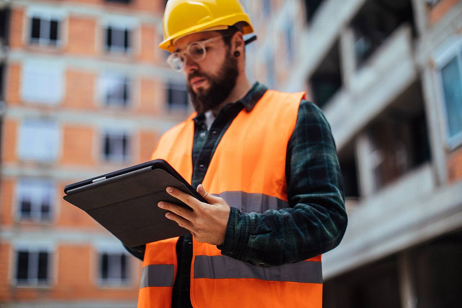 A construction working reviewing information on a tablet.