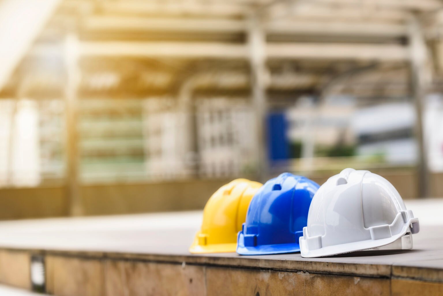 white, yellow and blue hard safety helmet hat for safety project of workman as engineer or worker, on concrete floor on city.